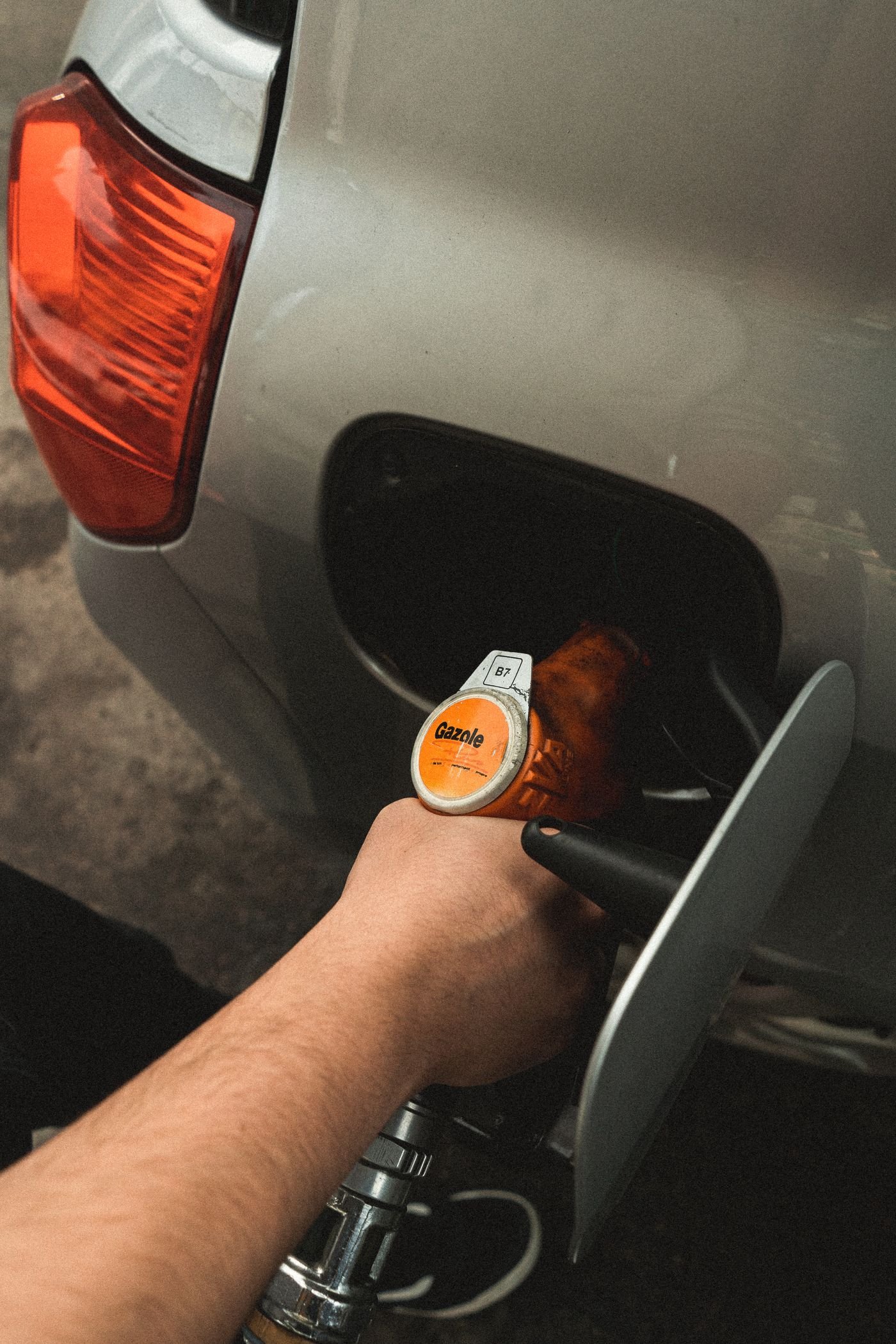 Fuel nozzle being held at the open filler neck of a car